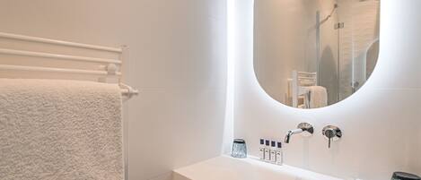A modern bathroom with a white vanity, a large mirror, and a towel rack.