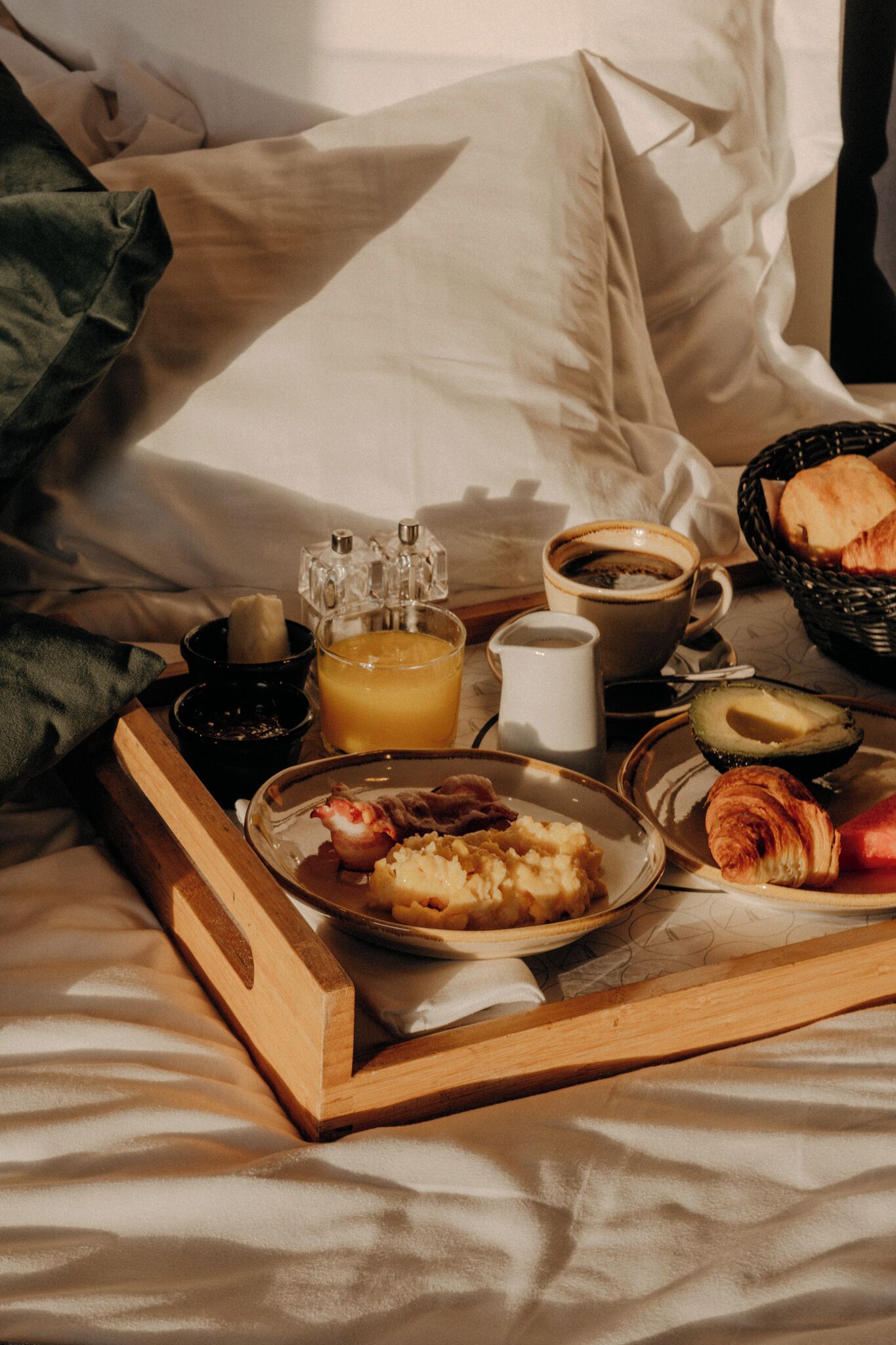 Bandeja de desayuno con comida y bebidas sobre una cama.