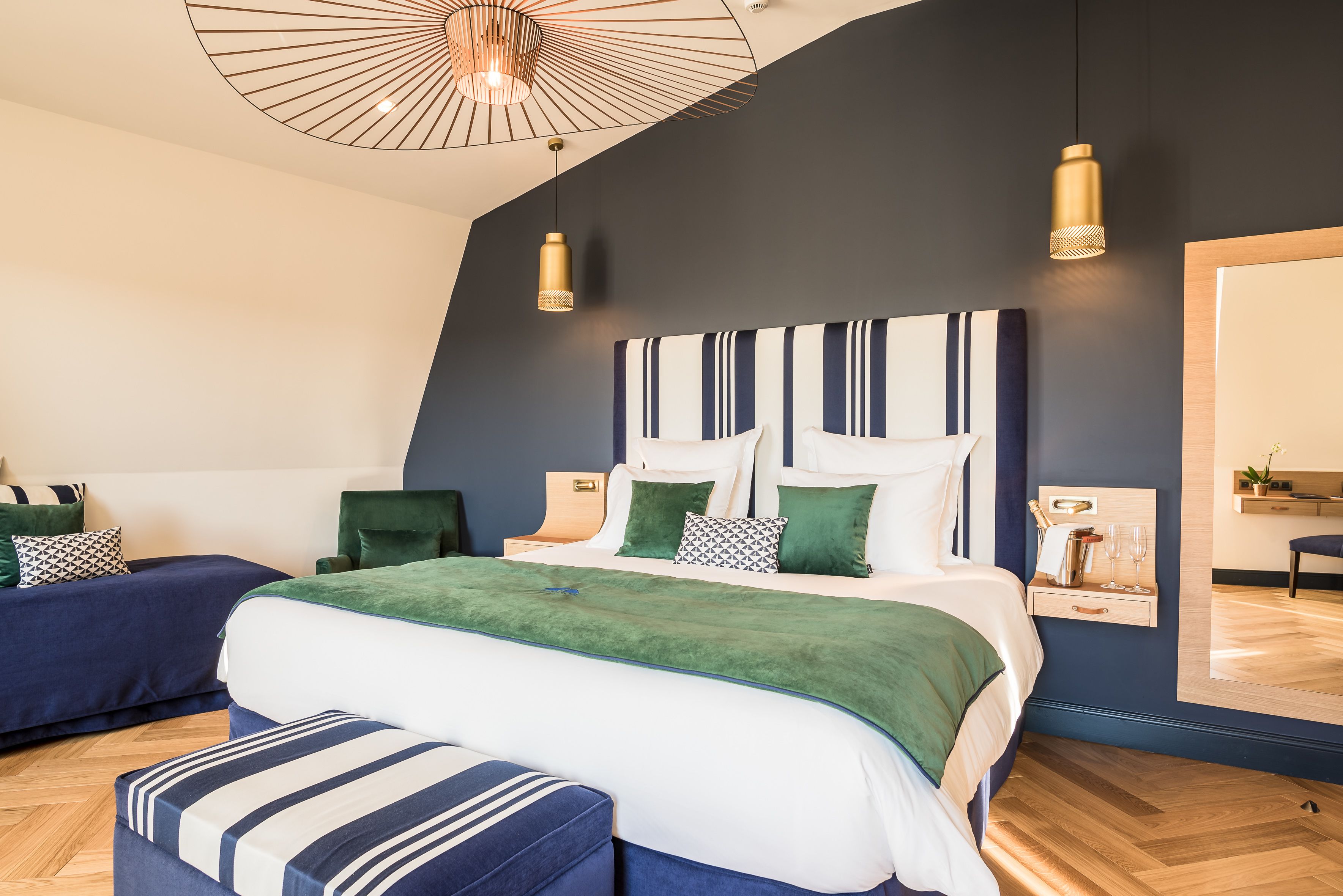 A modern bedroom with a large bed, two bedside tables, a mirror, and a hanging light fixture.