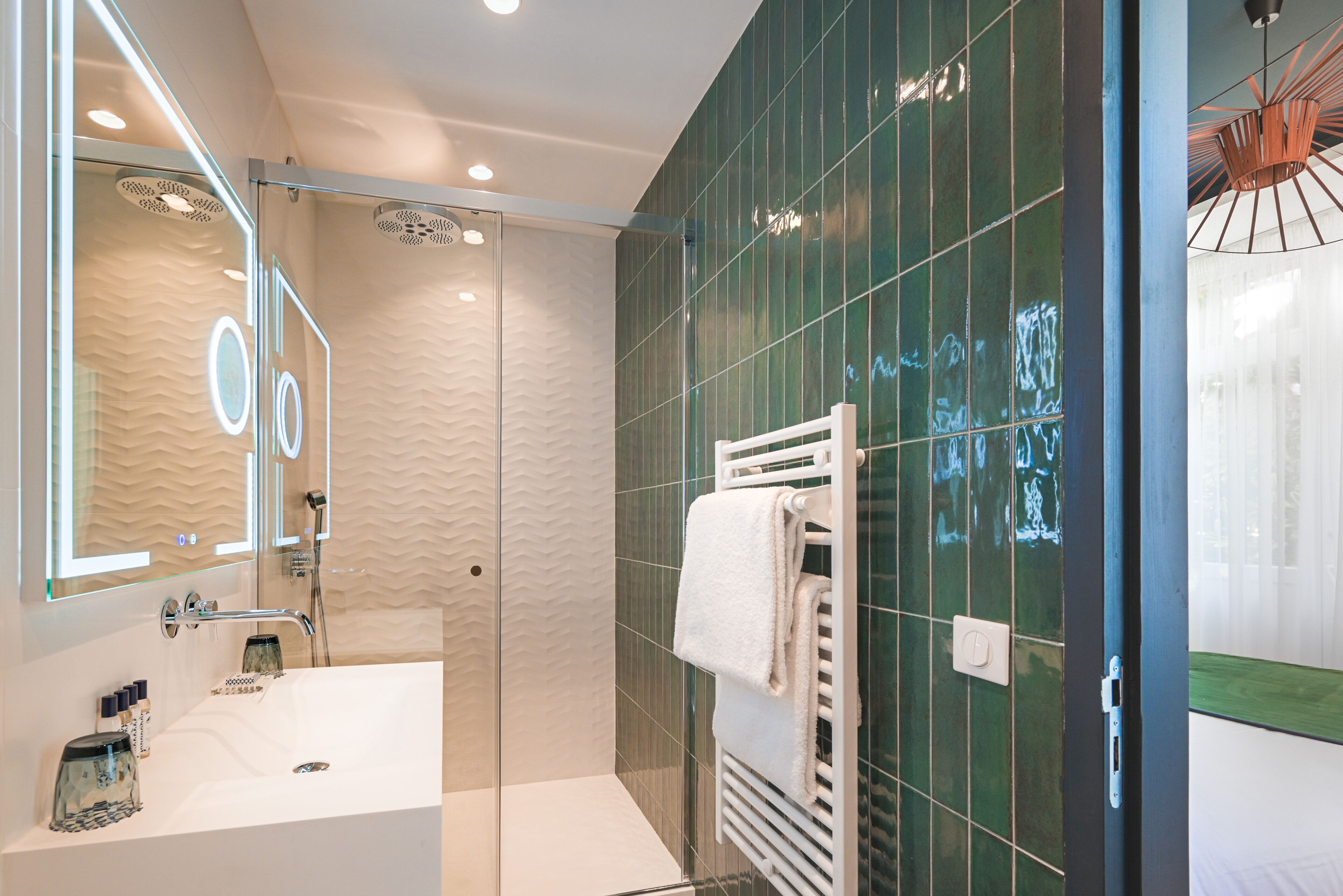 Un baño moderno con cabina de ducha de vidrio, un lavabo blanco y un perchero para toallas.