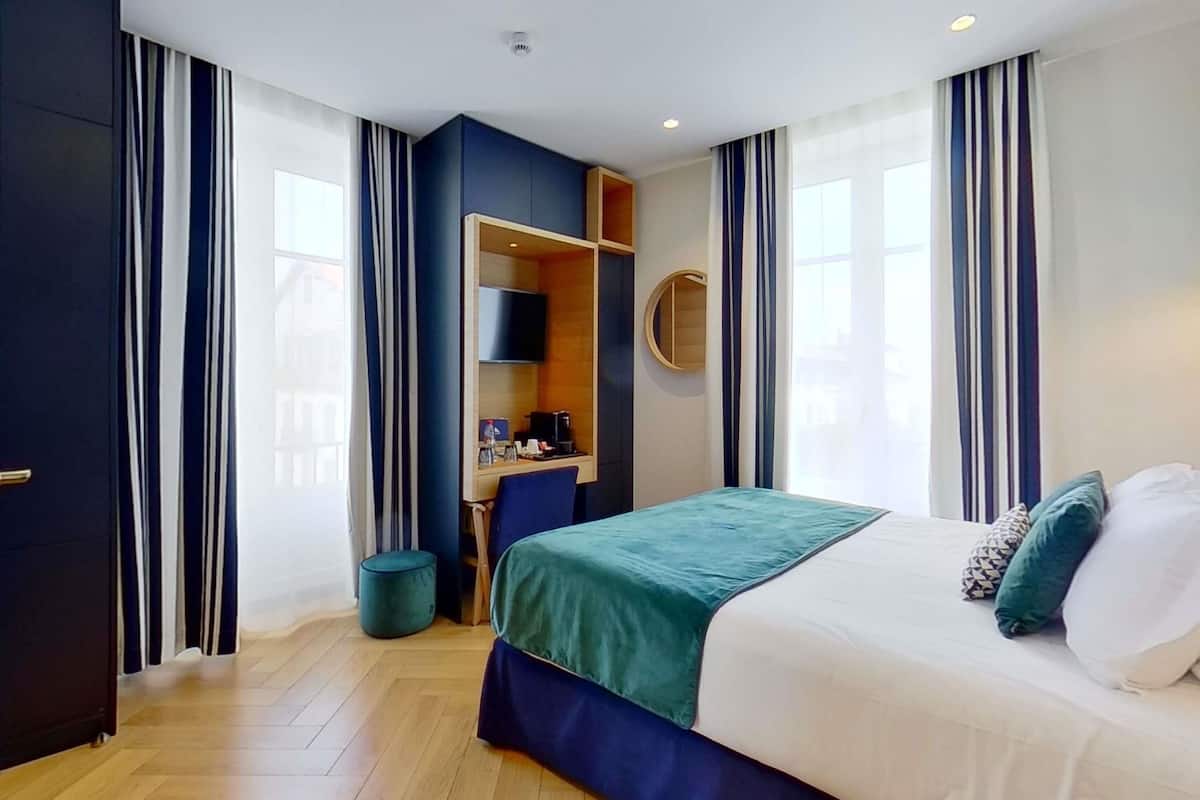 A hotel room with a bed, a desk, and a wardrobe.