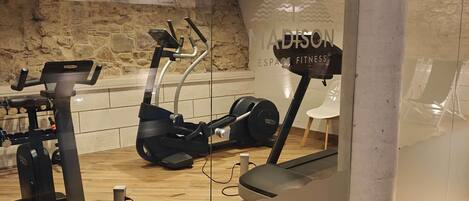 Un gimnasio con cintas de correr, una bicicleta estática y un banco de pesas.