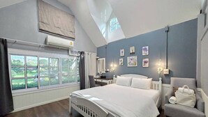 A bedroom with a large bed, a desk, a chair, and a view of the outdoors.