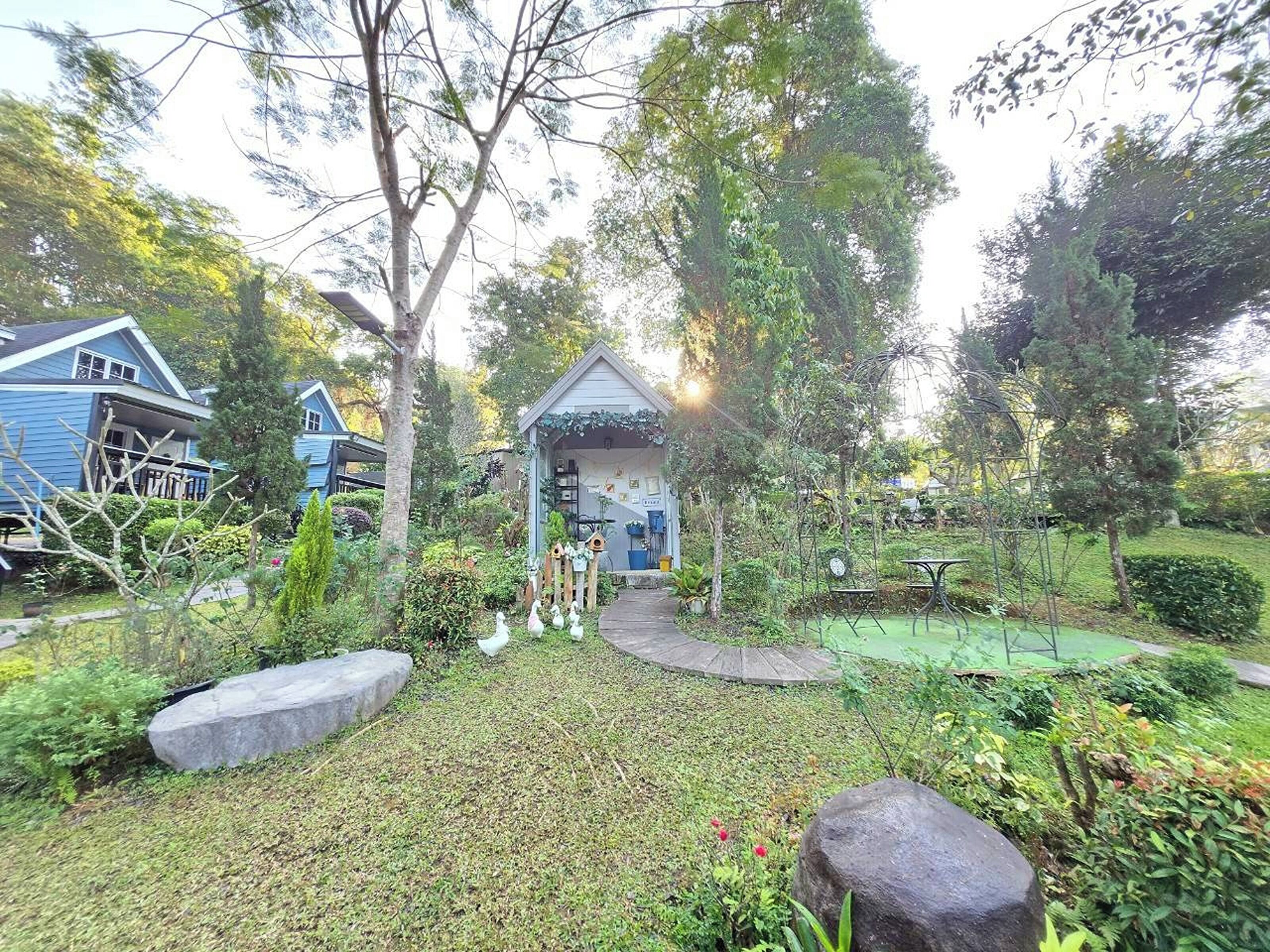 A garden with a small gazebo, a pathway, and a tennis court.