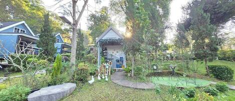 A garden with a small gazebo, a pathway, and a tennis court.