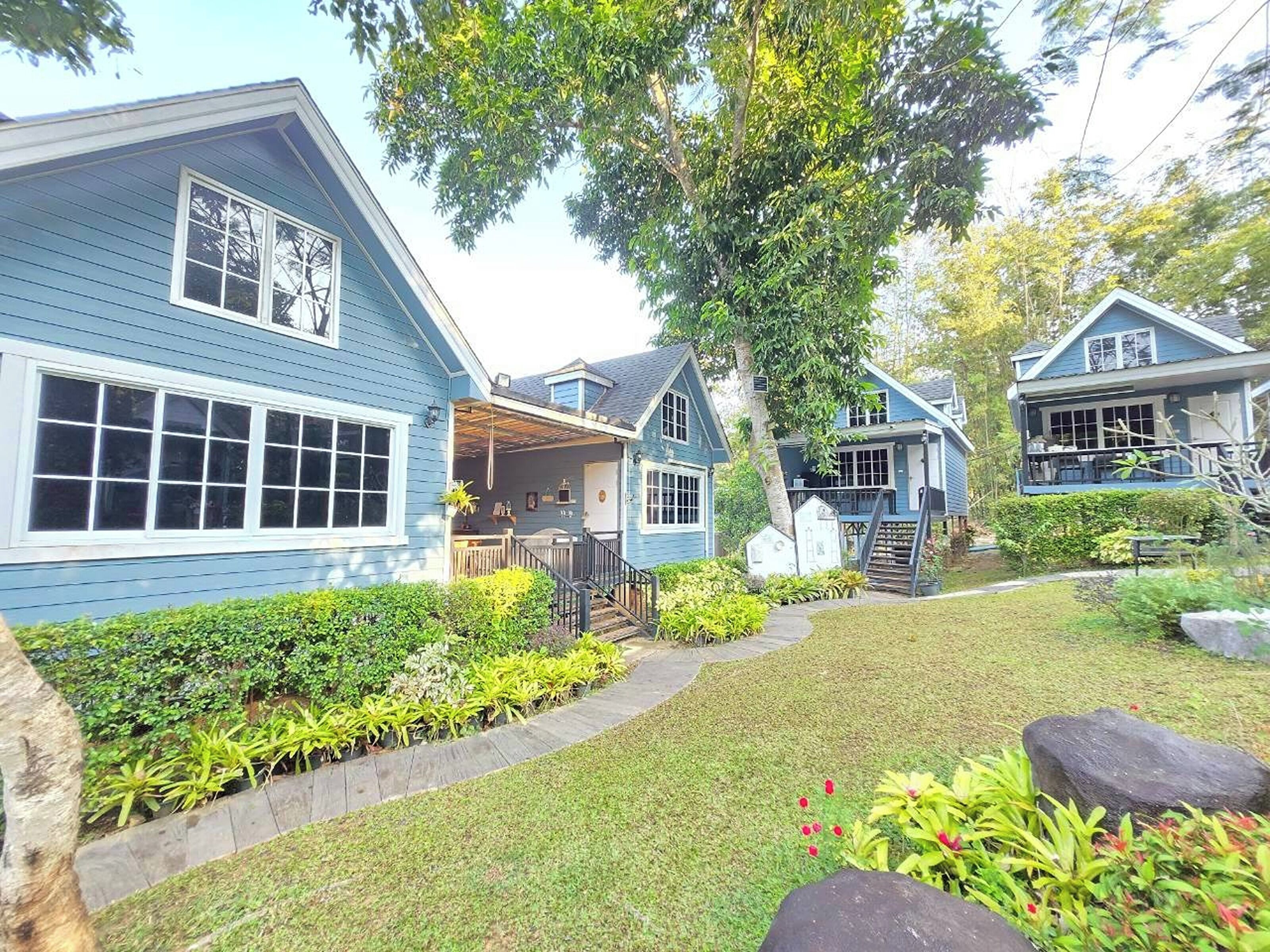 A row of blue houses with a covered porch and a well-maintained garden.