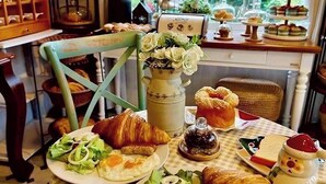 A breakfast table with croissants, eggs, and a vase of flowers.