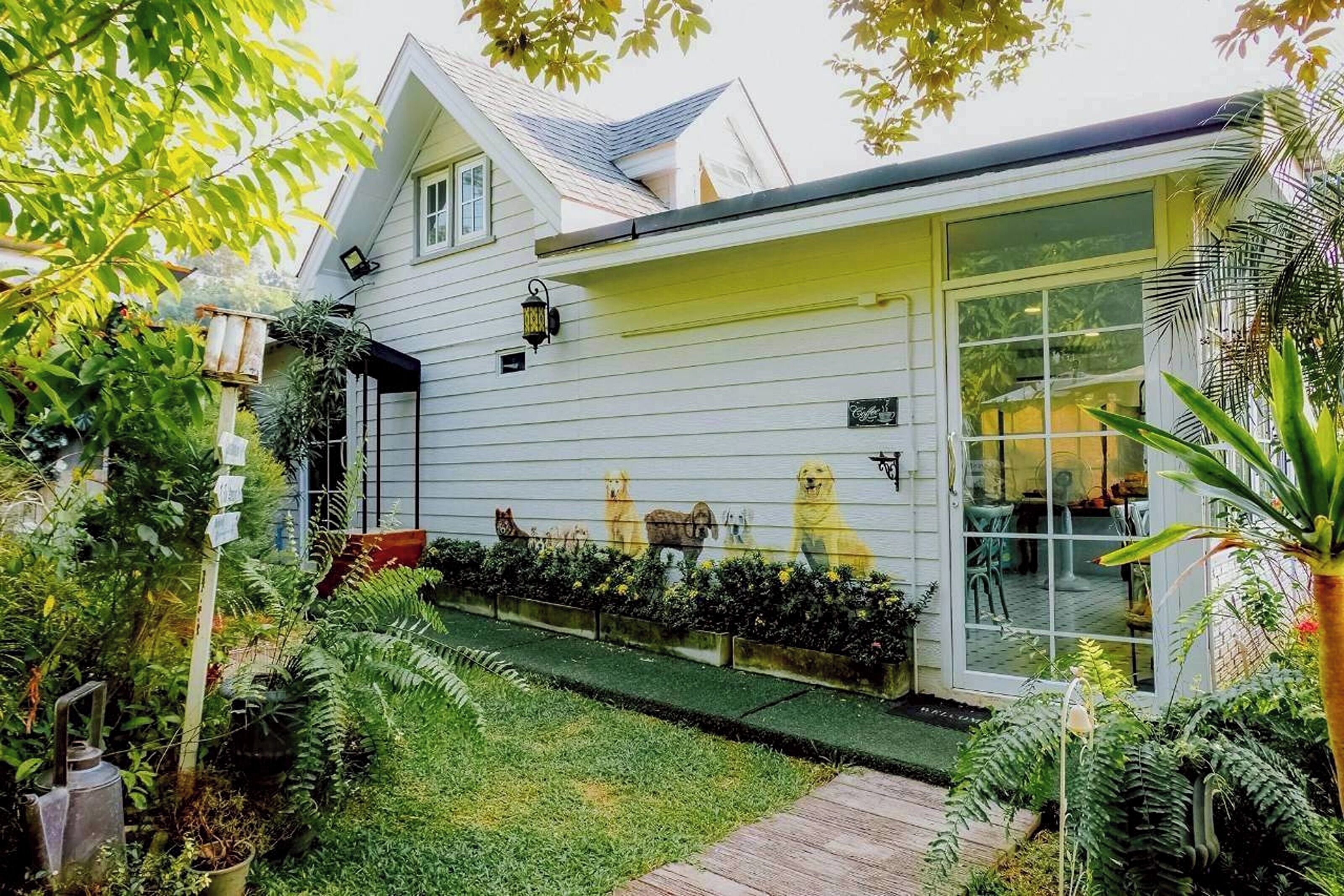 Een huis met een witte gevel, een overdekte veranda en een glazen deur die uitkomt op een patio.
