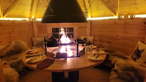 A cozy wooden cabin with a central fireplace, wooden furniture, and fur-covered cushions. - Le Féto (La Chapelle-d'Abondance)