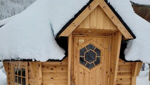 A wooden cabin with a snow-covered roof and a hexagonal window design. - Le Féto (La Chapelle-d'Abondance)