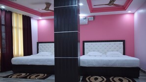 Habitación de hotel con dos camas, un pilar negro y un ventilador de techo.