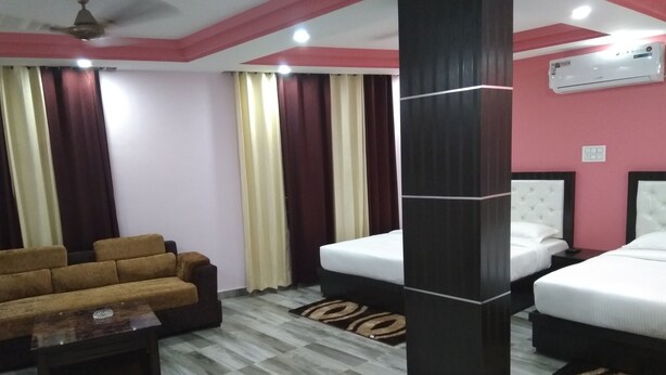 Una habitación de hotel con sofá, dos camas, una mesita de centro y un aire acondicionado.