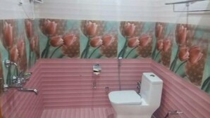 Un baño con una bañera rosa, un inodoro blanco y una zona de ducha.
