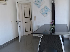 Un espace repas moderne avec une table en verre, une chaise noire et un vase rempli de fleurs.