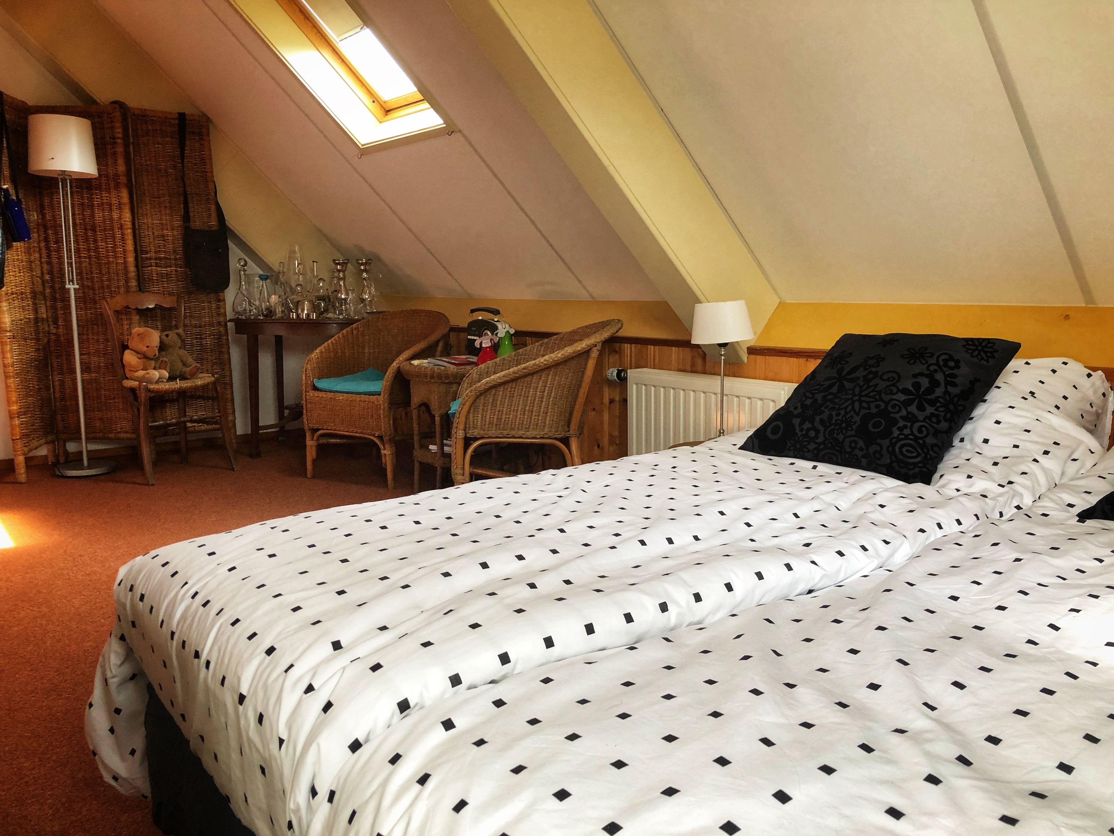 Ein Schlafzimmer mit einem Bett, einem Sessel, einem Tisch und einem Fenster.