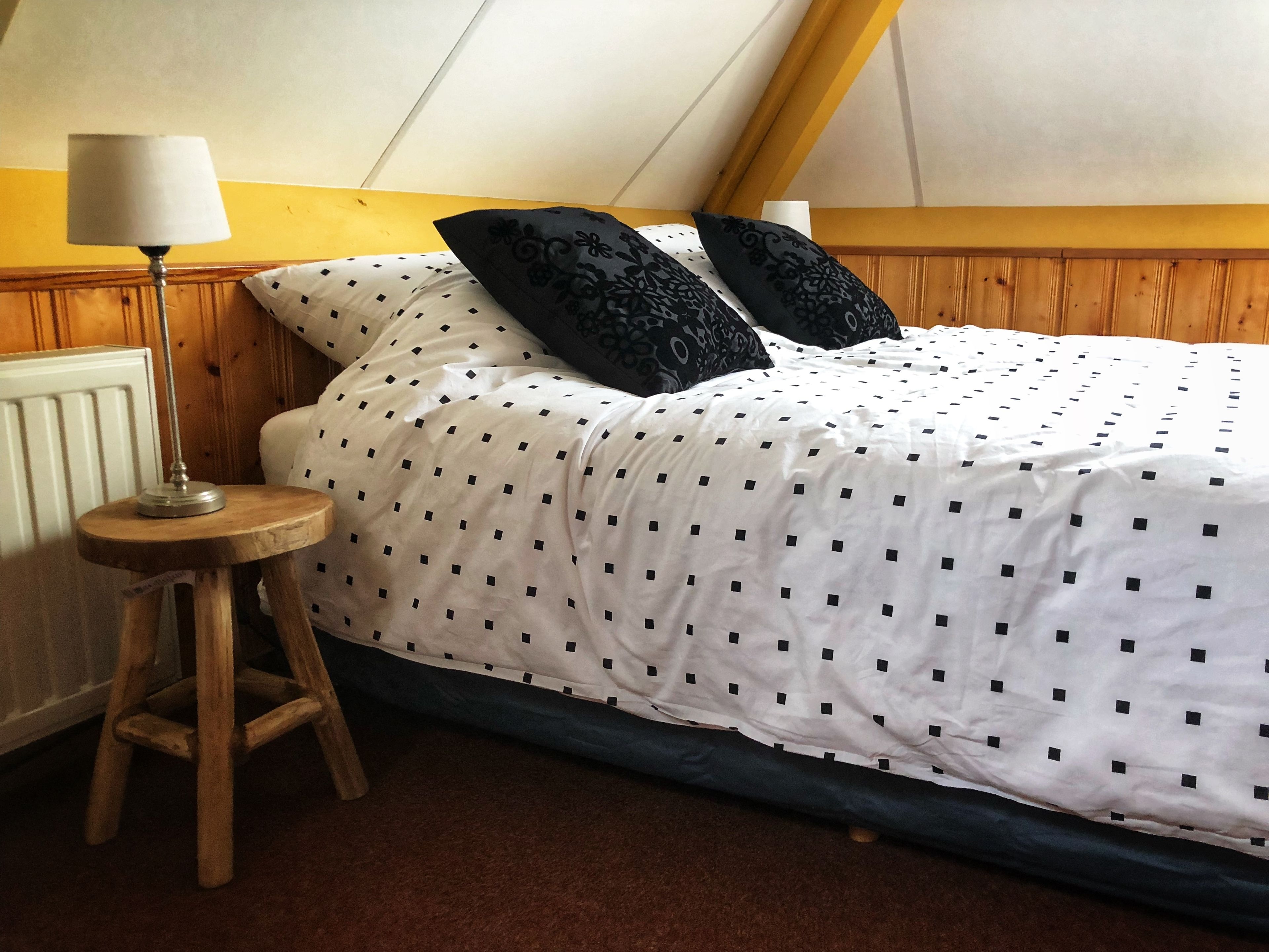 A bedroom with a bed, a nightstand, a lamp, and a wooden headboard.