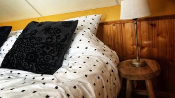 A bed with patterned pillows, a wooden nightstand with a lamp, and a yellow wall.