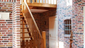 A room with a brick wall, a wooden staircase, a white door, and a window with bars. - B&B Zandhuizen (Zandhuizen)
