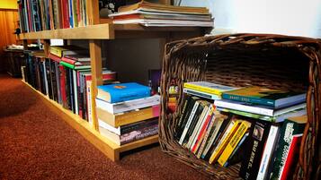 A bookshelf filled with books and a wicker basket containing more books.