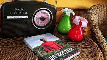 A Marquint radio, a book titled "It Was 2018", and two spray bottles on a wicker chair.