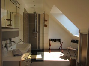 A modern bathroom with a shower, a sink, and a bench. - Maison Magdala (Fourmies)