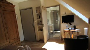 Ein Hotelzimmer mit Holzschrank, Bett mit weißem Bademantel, Schreibtisch mit Computer und Fernseher.