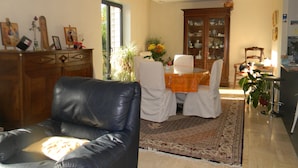 Ein Wohnzimmer mit einer Ledersofa, einem Esstisch mit Stühlen, einem Schrank und einem großen Fenster.