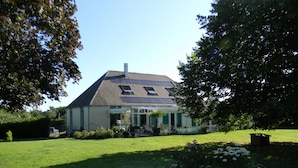 Ein Haus mit geneigtem Dach, Solaranlagen, einer überdachten Terrasse und einem gepflegten Rasen.