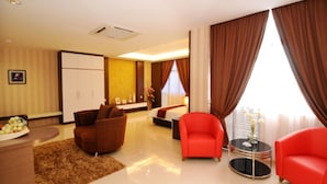 Quarto de hotel moderno com sofá, poltrona e uma pequena mesa com um vaso.