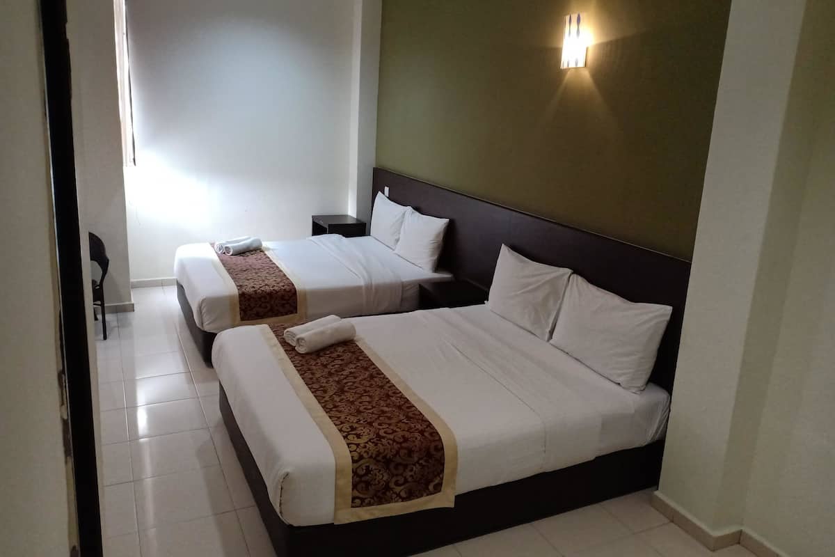 A hotel room with two beds, a nightstand, a wall-mounted light, and a window.