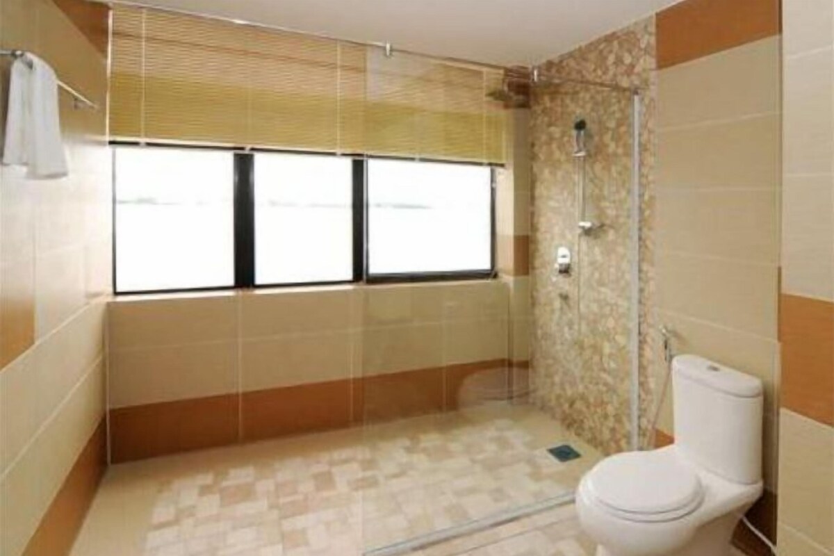 A bathroom with a shower, toilet, and a window with blinds.
