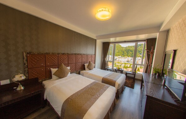 Habitación de hotel con dos camas, un ventanal con vistas, un escritorio y un televisor.