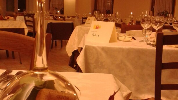 A dining area with tables set for a meal, a candle on a stand, and a decorative glass bowl with flowers. - Locanda Alla Rosa (Lusiana Conco)