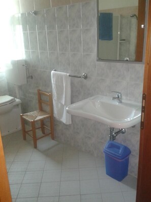 A bathroom with a toilet, a sink, a mirror, and a chair. - Locanda Alla Rosa (Lusiana Conco)