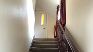 A carpeted staircase with wooden handrails, leading to a door with a small window. - The New Inn Guest House (Bridgend)
