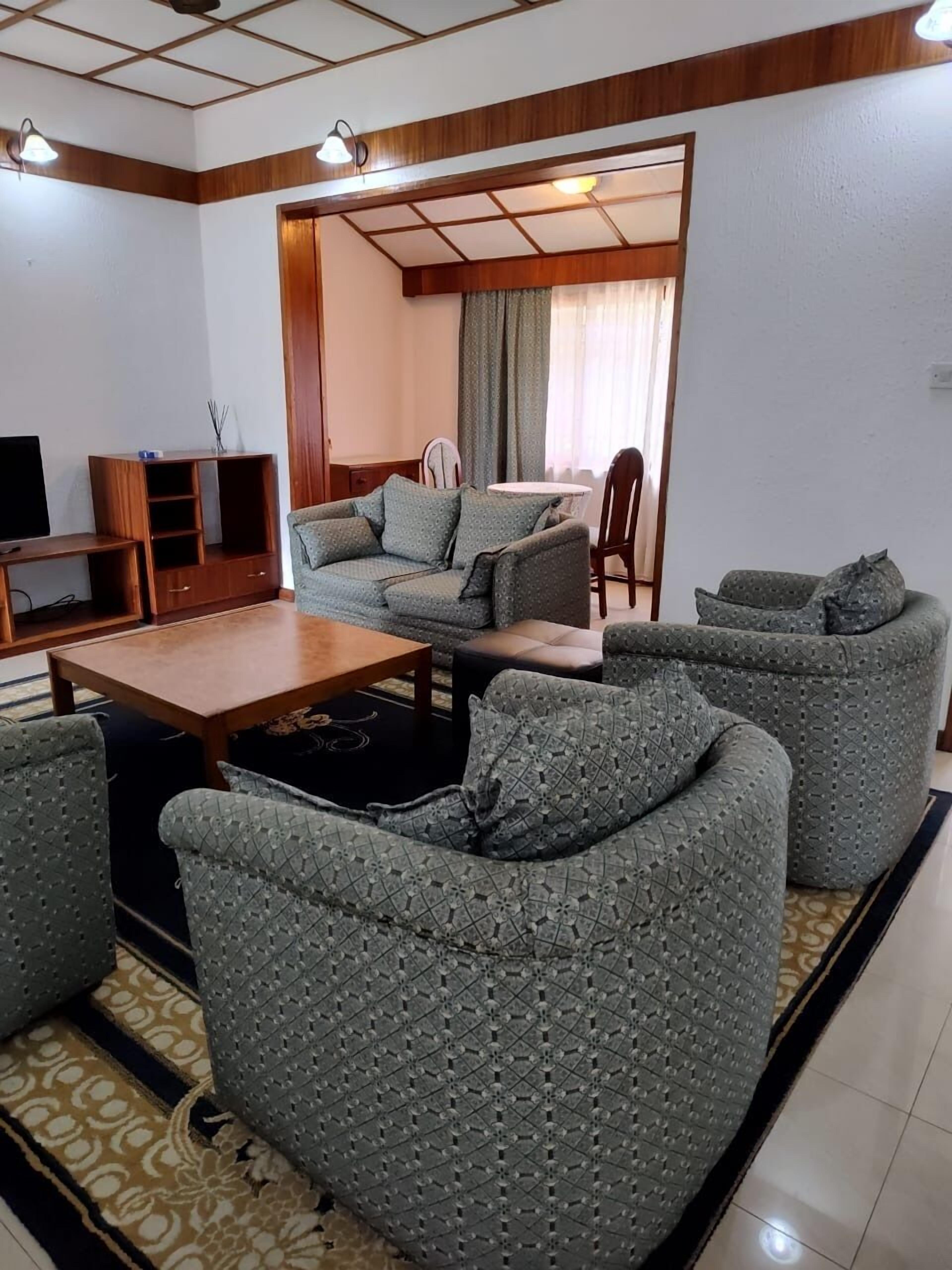 A living room with a sofa set, a coffee table, a TV stand, and a dining area with a table and chairs.