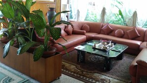 Una sala de estar con un sofá marrón, una mesa de centro y una planta en maceta.