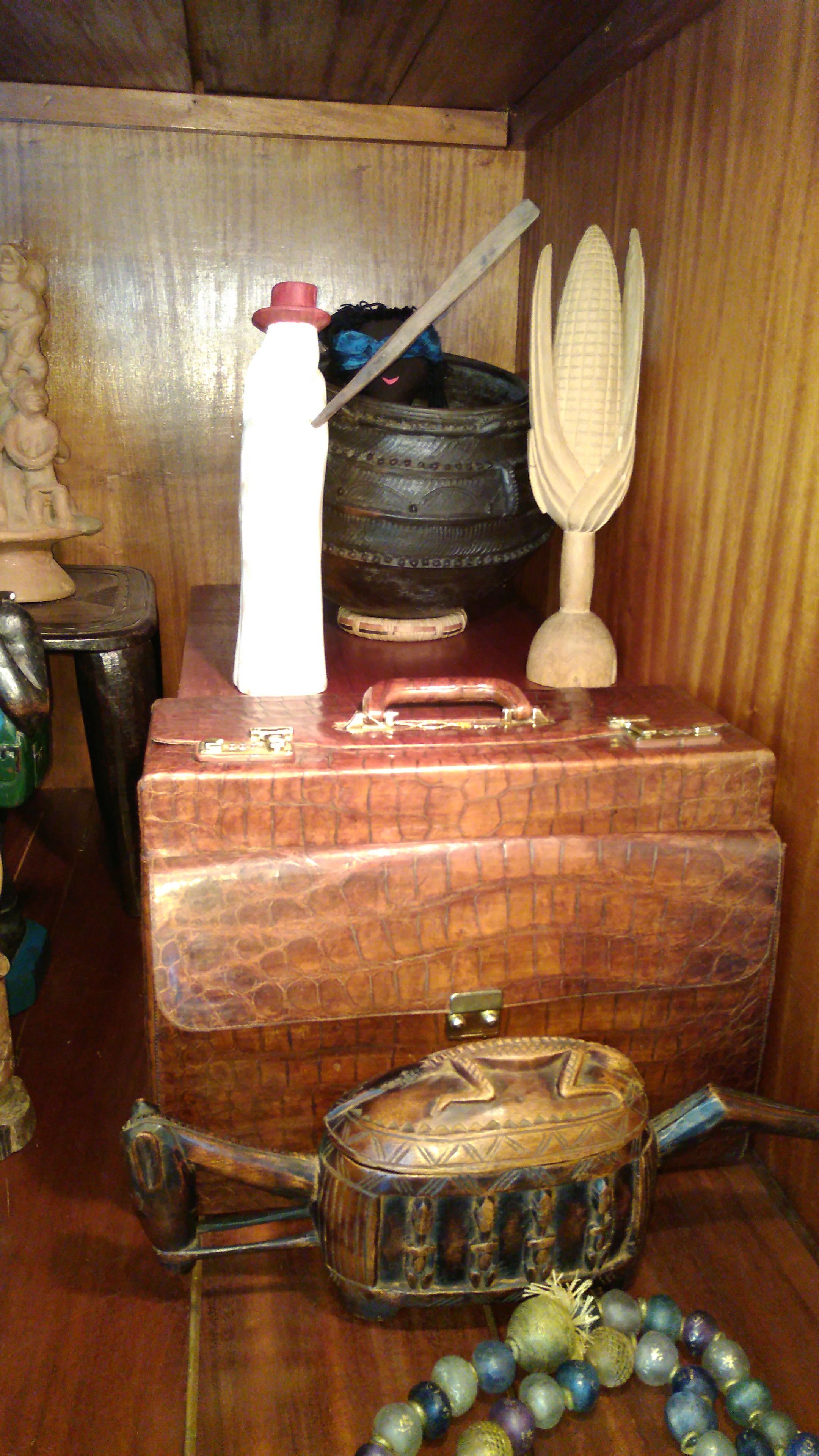 Un armadietto in legno con una valigia rossa, un contenitore metallico e un oggetto decorativo sopra.