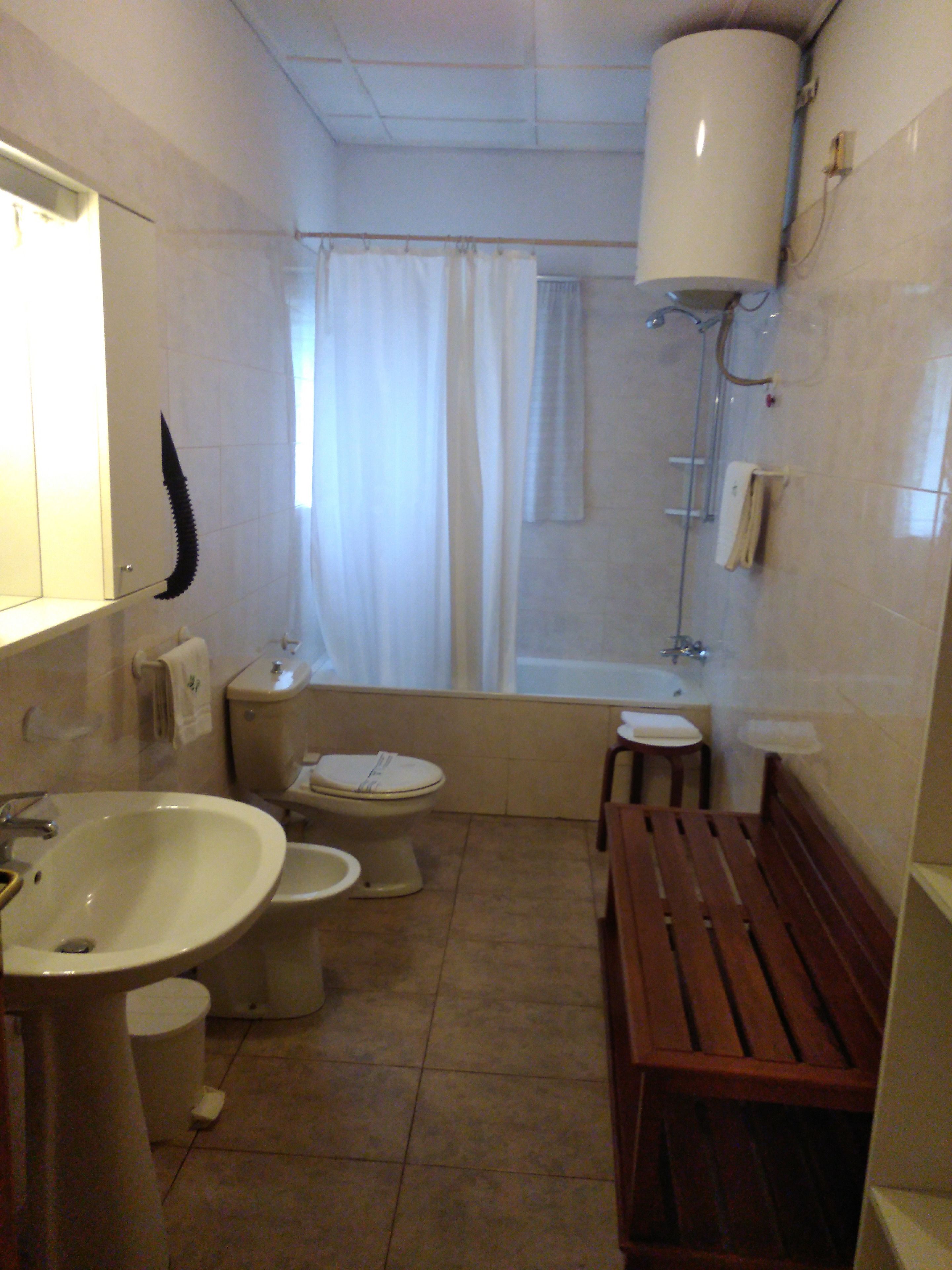 A small bathroom with a toilet, sink, and shower.