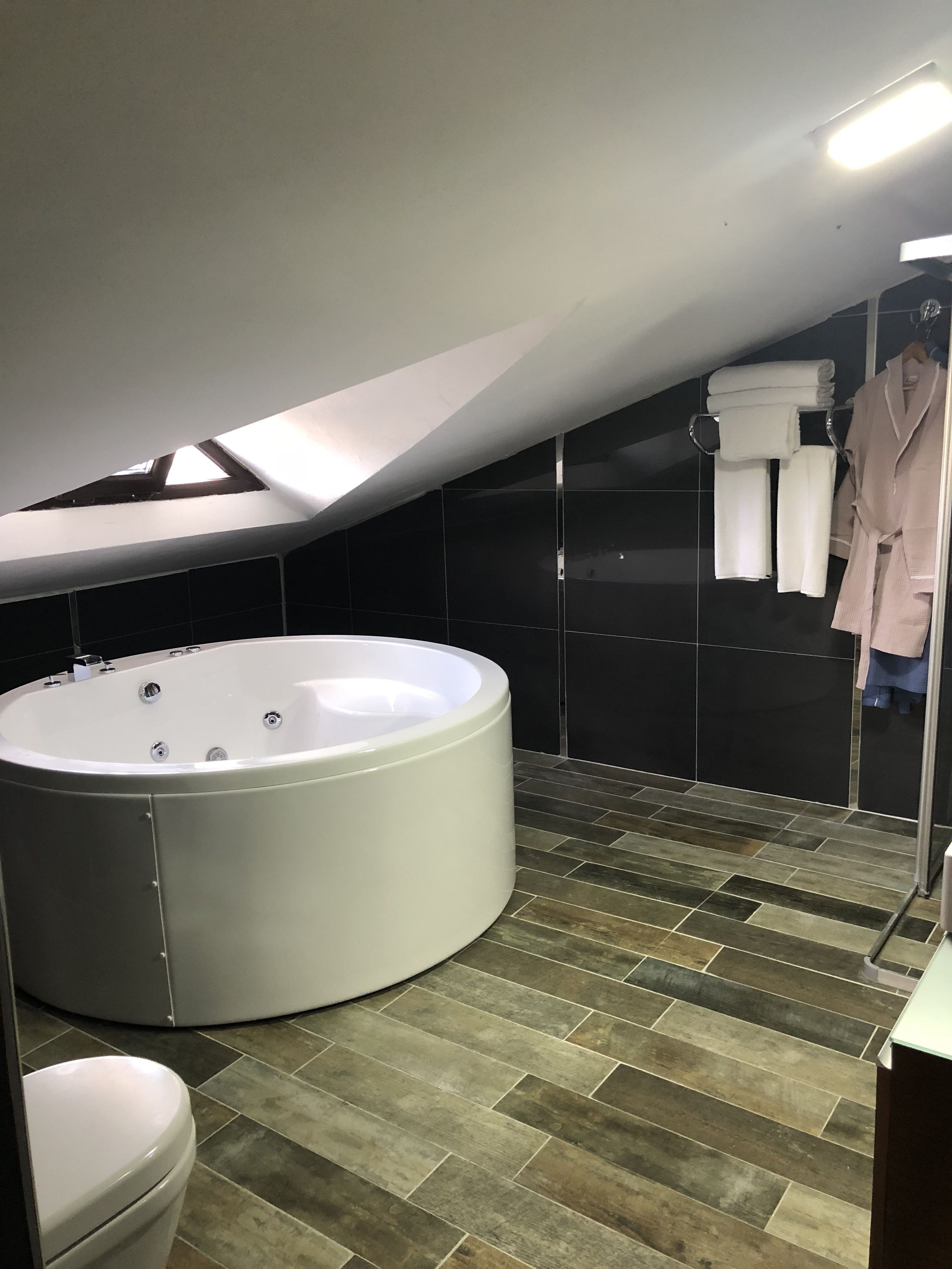 Un baño moderno con una bañera independiente grande, cabina de ducha de vidrio y un perchero con toallas dobladas ordenadamente.