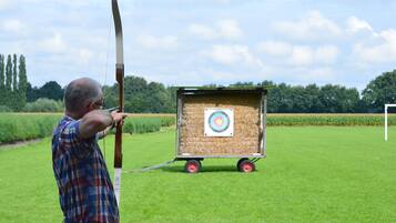 A man aiming an arrow at a target in an open field.