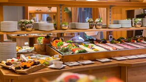 Un bufé con diversas opciones de comida, entre ellas frutas, verduras y carnes.