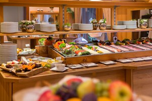 Un bufé con diversas opciones de comida, entre ellas frutas, verduras y carnes.