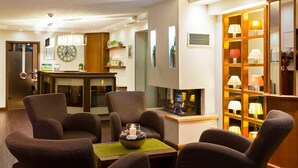 Un moderno vestíbulo de hotel con un área de descanso, chimenea y una exhibición de lámparas.