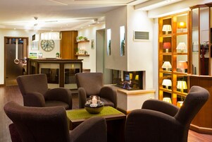 Un moderno vestíbulo de hotel con un área de descanso, chimenea y una exhibición de lámparas.
