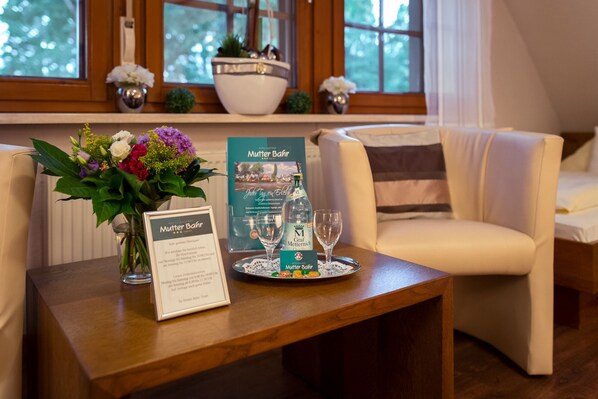 A hotel room with a wooden table, a vase of flowers, a brochure, and two wine glasses. - Hotel Mutter Bahr (Ibbenbueren)