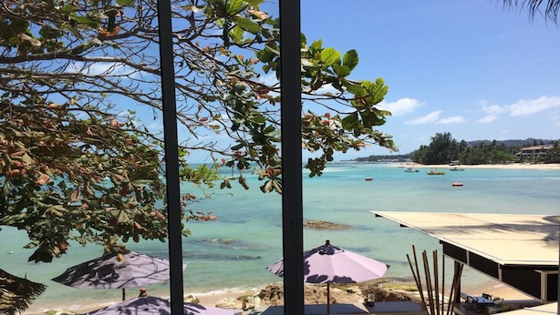 A beachside view with umbrellas, a sandy beach, and boats in the water. - Chill Inn Beach Cafe & Hostel (Koh Samui)