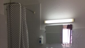 Une petite salle de bain avec un lavabo blanc, un miroir, un rideau de douche et des toilettes.