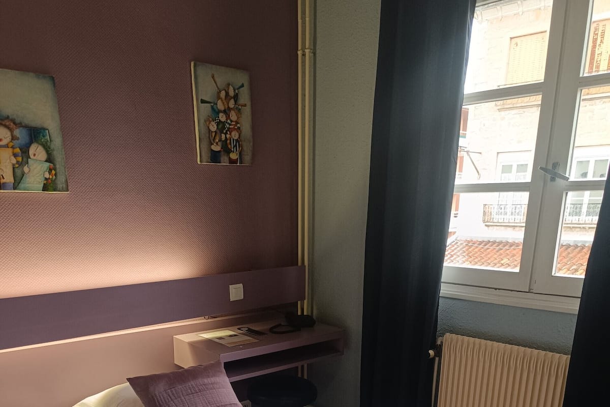 Ein Schlafzimmer mit Bett, Schreibtisch und Fenster.