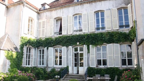 A two-story building with a garden patio, white shutters, and a small staircase leading to the entrance. - B&B Le Jardin de Carco (Chatillon-sur-Seine)